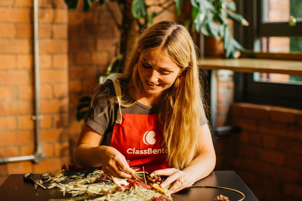 A smiling woman arranging a dried flower bouquet